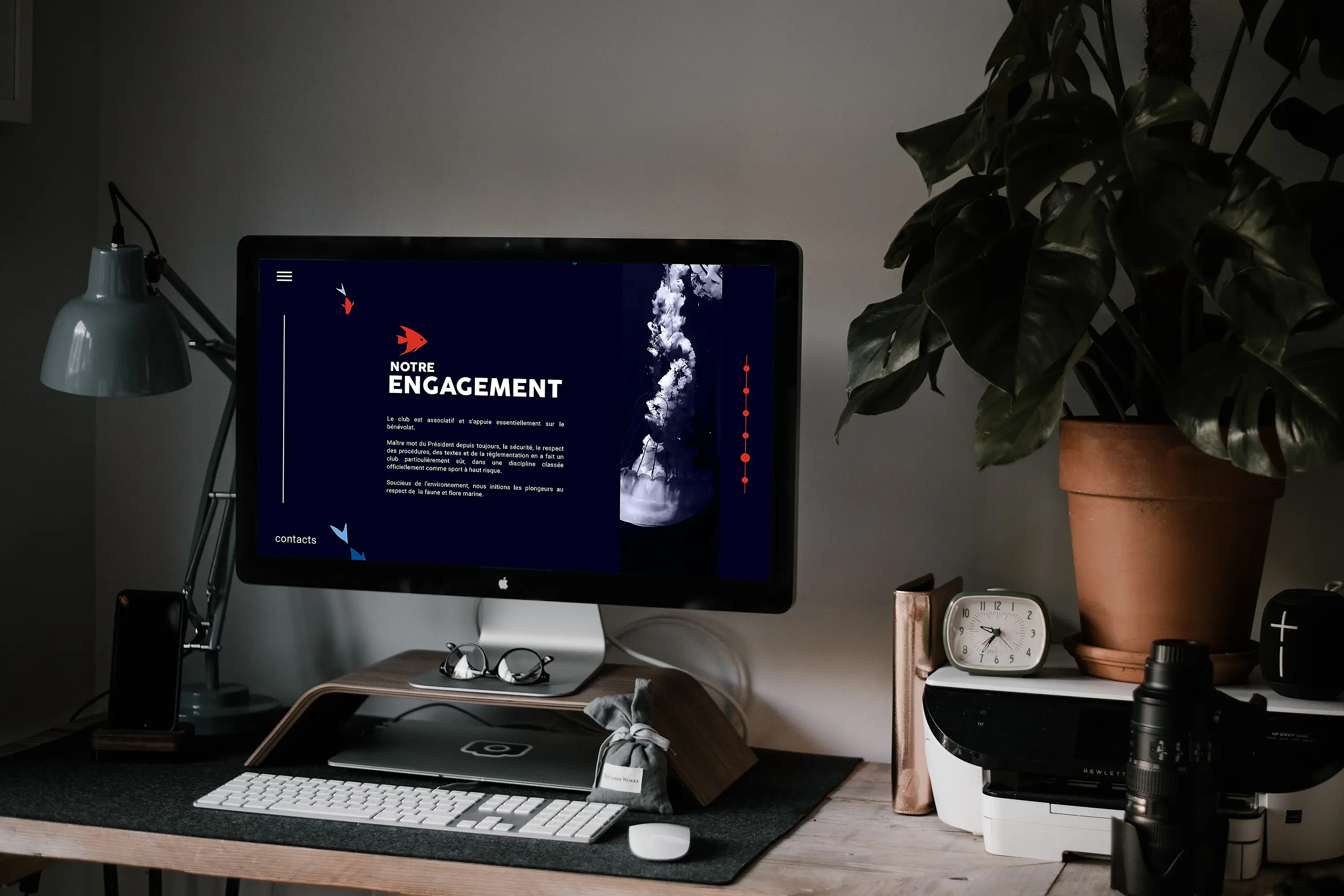 Un Imac sur un bureau affiche la page "engagement" du club de plongée.